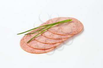 slices of deli meat with chives on white background