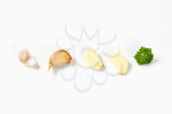 Unpeeled garlic clove and slices on white background