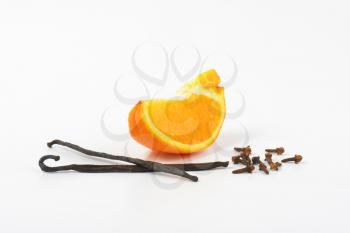 slice of orange, vanilla pods and cloves on white background