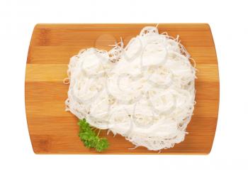 cooked rice noodles on wooden cutting board
