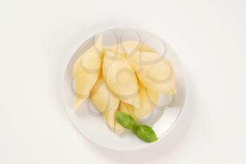 plate of cooked pasta shells on white background