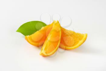 Fresh orange wedges and leaf on white background