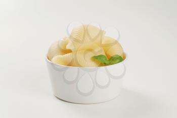 bowl of cooked pasta shells on white background