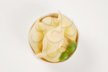 bowl of cooked pasta shells on white background