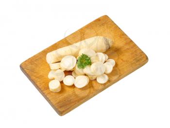 sliced parsley root on wooden cutting board
