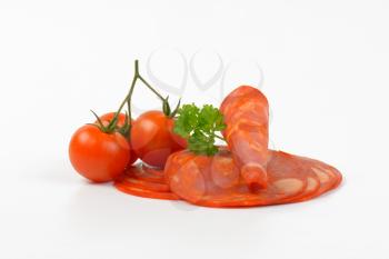 slices of chorizo salami and cherry tomatoes on white background