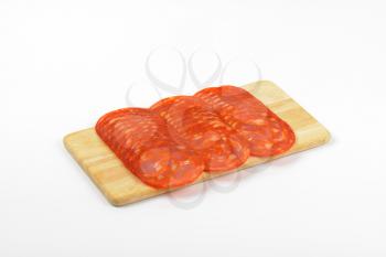 slices of chorizo salami ranked on wooden cutting board