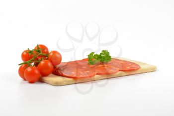 slices of chorizo salami and cherry tomatoes on wooden cutting board