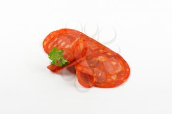 slices of chorizo salami with parsley on white background