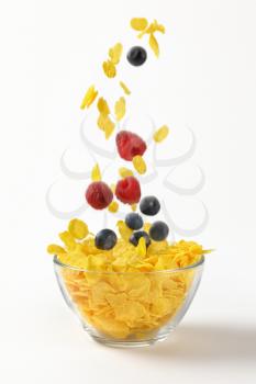 berry fruit falling into bowl of corn flakes on white background