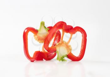 two slices of red bell pepper on white background