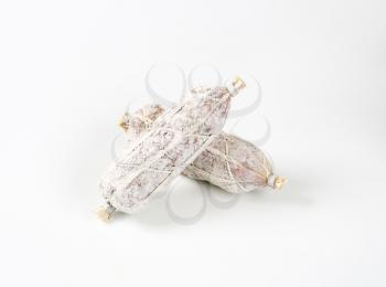 two French dry cured sausages on white background