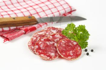 thin slices of dry cured sausage and kitchen knife