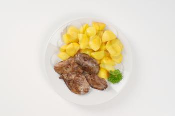 plate of pan fried potatoes and chicken liver on white background