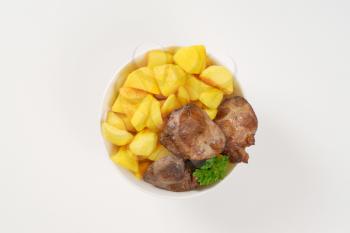 bowl of pan fried potatoes and chicken liver on white background