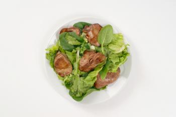 plate of pan fried liver with greens on white background