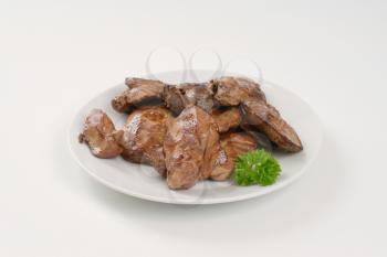 plate of pan fried chicken liver on white background