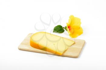 slice of gouda cheese with hibiscus flower on wooden cutting board