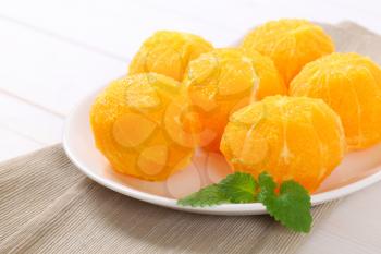 plate of whole peeled oranges on beige place mat - close up