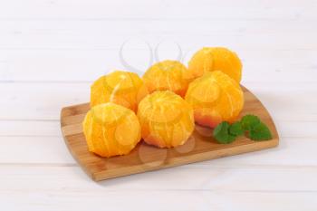 whole peeled oranges on wooden cutting board