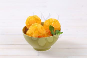 bowl of whole peeled oranges on white background