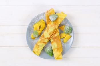 plate of thin pancakes (crepes) with fresh orange slices