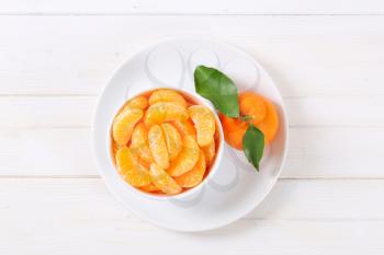 whole ripe tangerine with peeled slices in bowl