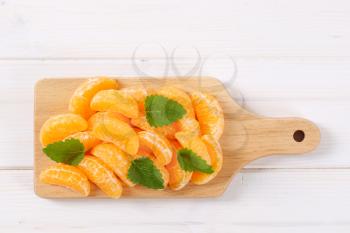 pile of fresh tangerine slices on wooden cutting board
