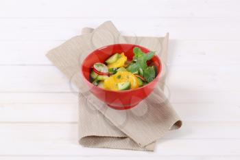 bowl of radish and cucumber salad with slices of orange