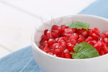 bowl of pomegranate seeds on blue place mat - close up
