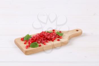 pile of pomegranate seeds on wooden cutting board