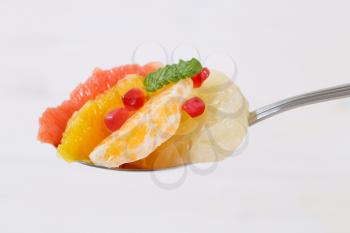 Spoonful of citrus fruit salad with pomegranate seeds