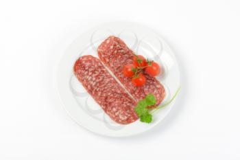 thin slices of salami and cherry tomatoes on white plate