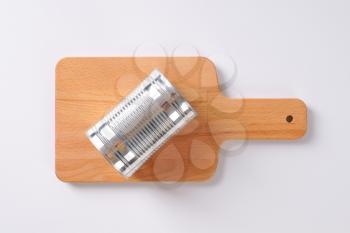 closed silver can on wooden cutting board