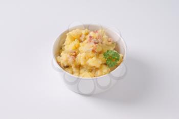 bowl of crushed potatoes with bacon on white background