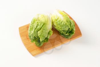 two heads of little gem lettuce on wooden cutting board