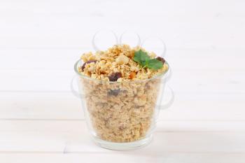 glass of granola with hazelnuts and  raisins on white wooden background