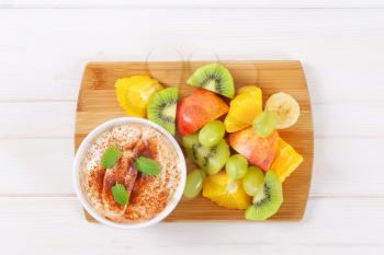 fresh fruit salad with cinnamon yogurt on wooden cutting board