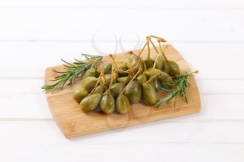 pile of pickled caper berries on wooden cutting board