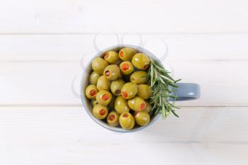 cup of green olives stuffed with red pepper on white background
