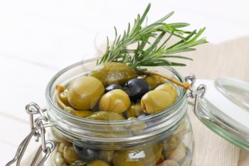 jar of pickled olives, capers and caper berries - close up
