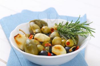 bowl of pickled olives, capers, caper berries and garlic