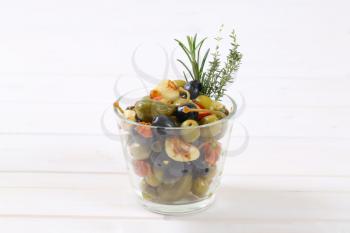 glass of pickled olives, capers, caper berries and garlic