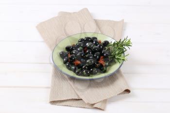 plate of black olives with dried tomatoes on beige place mat