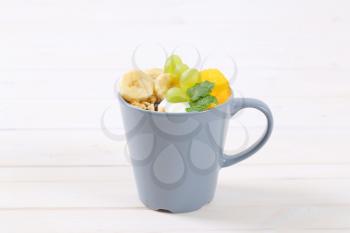 cup of muesli with yogurt and fresh fruit on white background