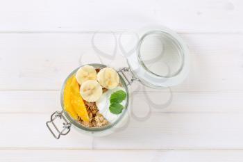 jar of muesli with yogurt and fresh fruit on white background