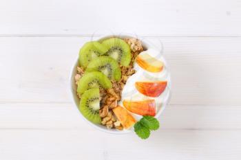 bowl of muesli with yogurt and fresh fruit on white background