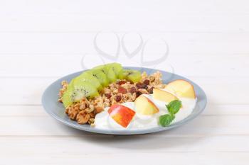 plate of muesli with yogurt and fresh fruit on white background