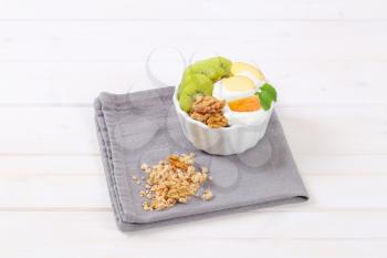 bowl of muesli with yogurt and fresh fruit on grey place mat