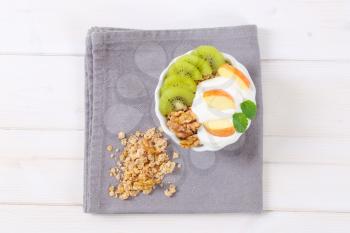 bowl of muesli with yogurt and fresh fruit on grey place mat